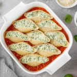 O Conchiglione Recheado é Uma Opção Perfeita Para Quem Busca Um Prato Saboroso E Sofisticado. Seu Formato De Concha Permite Recheios Variados, Tornando-o Versátil Para Diferentes Ocasiões. Como Surgiu O Conchiglione? O Conchiglione Tem Origem Italiana, Sendo Uma Das Diversas Variedades De Massas Desenvolvidas Na Região Da Campânia. Seu Nome Vem Do Italiano "conchiglia", Que Significa Concha, Remetendo Ao Seu Formato Característico. Tradicionalmente, Ele é Servido Recheado E Gratinado, Com Molhos Que Variam Entre Tomate E Bechamel. Quantas Calorias Tem O Conchiglione? As Calorias Do Conchiglione Variam Conforme O Recheio E O Molho Utilizado. Em Média, Uma Porção De 200g De Conchiglione Recheado Com Queijo E Molho De Tomate Possui Cerca De 350 A 450 Calorias. Informações Nutricionais Da Receita E Rendimento Tipo De Receita: Massa Recheada Tempo De Preparo: 30 Minutos Tempo De Forno: 20 Minutos Tempo Total: 50 Minutos Rendimento: 4 Porções Calorias Por Porção: Aproximadamente 400 Kcal Ingredientes 300g De Conchiglione (massa Em Formato De Concha) 250g De Ricota (para Um Recheio Cremoso) 100g De Espinafre Cozido E Picado (opcional, Para Um Toque Mais Saudável) 200g De Queijo Muçarela Ralado (para Gratinar) 50g De Parmesão Ralado (para Um Sabor Extra) 1 Ovo (para Dar Liga Ao Recheio) 500ml De Molho De Tomate (para Cobrir E Deixar Suculento) 2 Colheres De Sopa De Azeite De Oliva (para Refogar) 2 Dentes De Alho Picados (para Temperar) Sal E Pimenta-do-reino A Gosto (para Ajustar O Sabor) Equipamentos Necessários Panela Grande Para Cozinhar A Massa Assadeira Para Levar Ao Forno Frigideira Para Refogar O Espinafre (se Utilizar) Tigela Para Misturar O Recheio Modo De Preparo 1. Cozinhando A Massa Ferva água Com Sal E Cozinhe O Conchiglione Até Ficar Al Dente. Escorra E Reserve. 2. Preparando O Recheio Misture A Ricota, O Espinafre, O Ovo, Metade Da Muçarela E Tempere Com Sal E Pimenta. 3. Montagem Do Prato Recheie Cada Conchiglione Com A Mistura De Ricota E Espinafre. Distribua-os Em Uma Assadeira Coberta Com Molho De Tomate. 4. Finalização E Forno Cubra Com Mais Molho De Tomate, Polvilhe Muçarela E Parmesão. Leve Ao Forno Preaquecido A 180ºC Por 20 Minutos Até Gratinar. Dicas Extras Experimente Outros Recheios Como Frango Com Catupiry Ou Carne Moída Com Requeijão. Para Um Toque Gourmet, Adicione Nozes Picadas Ao Recheio De Ricota. Sugestões De Acompanhamento O Conchiglione Recheado Combina Perfeitamente Com: Salada Verde Com Molho Balsâmico Pão Italiano Crocante Vinho Tinto Leve, Como Merlot Ou Pinot Noir Como Armazenar Geladeira: Armazene Em Recipiente Fechado Por Até 3 Dias. Freezer: Congele Por Até 2 Meses, Descongelando Na Geladeira Antes De Reaquecer. Reaquecimento: Use O Forno A 180ºC Por 15 Minutos Ou Micro-ondas Por 2 Minutos. Considerações Finais O Conchiglione Recheado é Uma Receita Fácil, Saborosa E Perfeita Para Impressionar Em Qualquer Ocasião. Experimente E Surpreenda-se! FAQs Posso Usar Outro Tipo De Queijo? Sim! Cottage, Cream Cheese Ou Queijo Minas Também Funcionam Bem. Qual é O Melhor Molho Para Acompanhar? Molho De Tomate é O Mais Usado, Mas Molho Branco Também é Uma ótima Opção. Posso Fazer A Receita Sem Forno? Sim! Basta Aquecer No Micro-ondas Até O Queijo Derreter. O Conchiglione Pode Ser Feito Com Recheio Vegano? Sim! Substitua Os Queijos Por Tofu Temperado E Use Molho De Castanhas. Qual Vinho Harmoniza Melhor Com Esse Prato? Tintos Leves Como Merlot Ou Chianti Combinam Muito Bem.